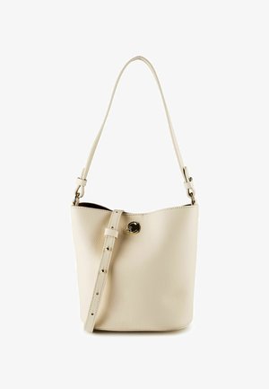 Eimerförmige Tasche aus cremefarbenem Leder mit verstellbarem Schulterriemen und goldenem, rundem Verschluss auf der Vorderseite vor weißem Hintergrund.