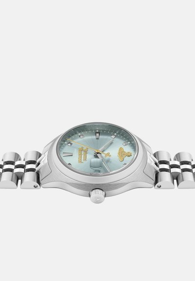 Montre en acier inoxydable argenté avec un cadran turquoise, des index horaires argentés et un bracelet en métal. Présente un motif texturé et un détail de couronne.