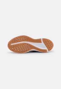 Shoe sole with a textured rubber bottom in orange and white, featuring a patterned grip design and a central groove for flexibility.