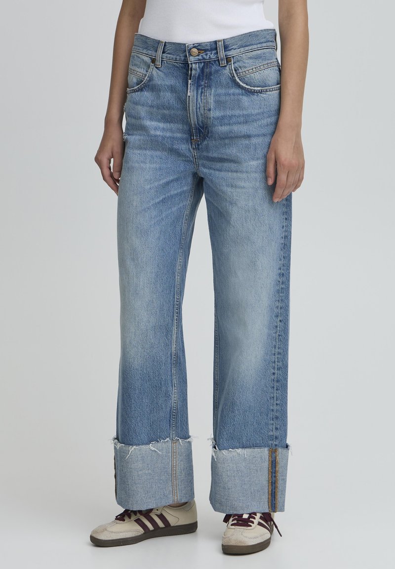 Brede blauwe denim jeans met een rafelige zoom, voorzien van een traditionele vijf-pocket ontwerp en een knoopsluiting in de taille.