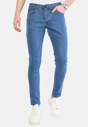 Blauwe denim slim-fit jeans met vijf zakken, een knoopsluiting en lichte vervaging. Gecombineerd met witte sneakers voor een casual look.
