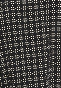 Schwarzer Stoff mit einem sich wiederholenden weißen Quadratmuster, strukturiert mit einer weichen, glatten Oberfläche. Das Design besteht aus kleinen Kreuzmotiven.