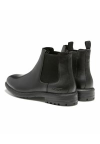 Bottines Chelsea en cuir noir avec des panneaux élastiques sur les côtés, bout rond, dos texturé et semelle en caoutchouc robuste. Logo subtil sur le talon.