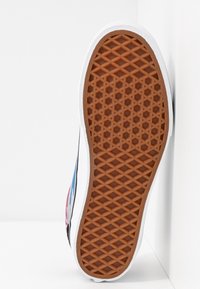 Semelle de chaussure avec une plateforme en caoutchouc présentant un motif en losange marron, bordé de blanc. Le design latéral comporte des accents bleus et roses.