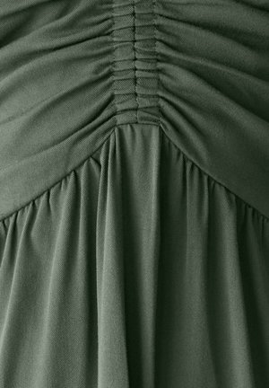 Tume roheline kleit, mis on varustatud volditud tekstuuriga rinnaosas ja voolavate kangast riidekattidega. Sile, kerge materjal, millel on õrn sära.