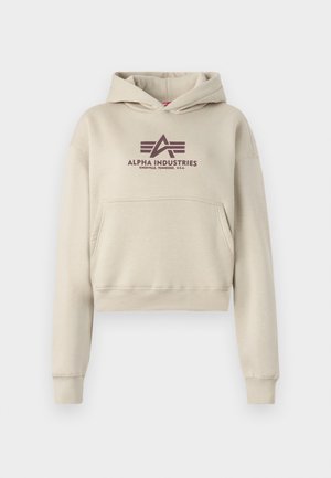 Beige, rövidített kapucnis pulóver, elülső zsebbel és sötétlila "Alpha Industries Knoxville, Tennessee, U.S.A." logóval a mellkasán.