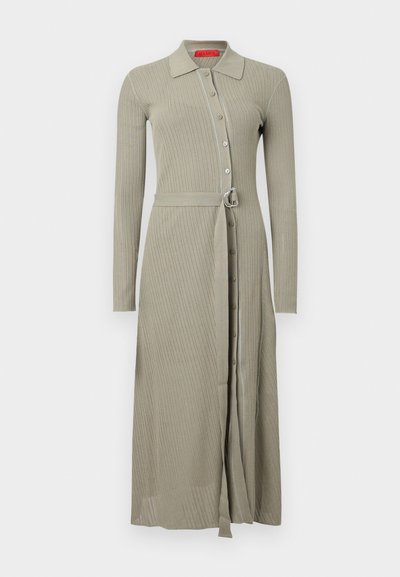 Robe longue côtelée en kaki doux. Comprend un col avec boutons sur le devant et une ceinture en tissu avec une boucle argentée. Manches longues.