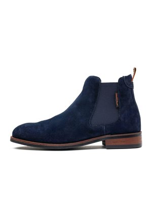 Navy blue suede Chelsea boot with brown sole, elastic side panel, and pull tab at the heel, shown in profile on a white background.