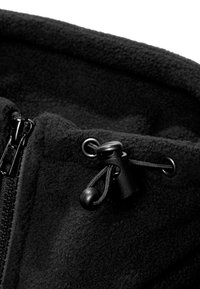 Tissu polaire noir avec fermeture éclair noire et verrou réglable à cordon sur un vêtement ou accessoire d’hiver.