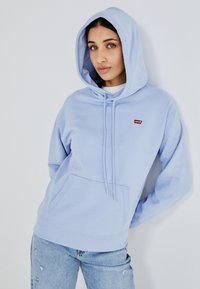 Felpa con cappuccio di colore blu chiaro, dotata di tasca frontale e un piccolo logo rosso Levi's. Realizzata in tessuto morbido, con coulisse e polsini a coste.