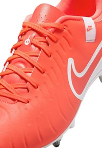 Nike jalgpalliketsid erksast oranžist sünteetilisest materjalist. Omavad tekstuurset ülemist osa, valget logo ja kontrastseid paelu. Kavandatud heaks haardeks rohelisel murul.