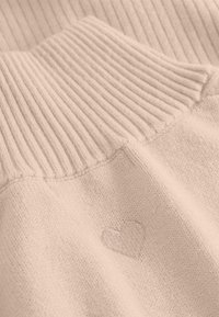 Gebreide trui in lichtbeige met een geribde kraag en subtiele hartborduursel. Zachte textuur met een ontspannen, casual ontwerp.