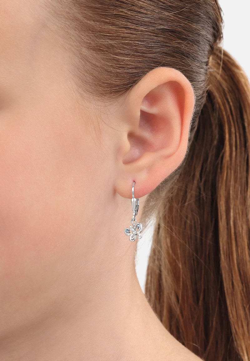 Pendientes de gota plateados con un diseño de gancho. La flor presenta un elaborado detalle y un acabado pulido, colgando justo debajo del lóbulo de la oreja.