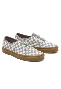 Un paio di sneaker low-top Vans con motivo a scacchi beige e bianco, lacci verdi e bianchi, e suole in gomma color miele su sfondo bianco.