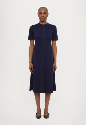 Marineblaues Midikleid mit kurzen Ärmeln, einem runden Ausschnitt und einer zentralen Naht. Hergestellt aus einem glatten Stoff, der dezente kontrastierende Nähte aufweist.