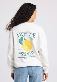 White sweatshirt with a lemon graphic and text on the back. Features relaxed fit, soft fabric, and dropped shoulders.