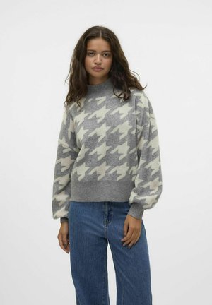 Grå och krämfärgad mönstrad tröja med houndstooth-design, ribbad hög hals och ballongsärmar, tillsammans med ljusblå jeans.