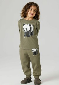 Olivengrønt sett med genser og joggebukse, med et pixelert panda-motiv på begge plagg. Laget av myk bomull, avslappet passform og ribbestrikkede mansjetter.