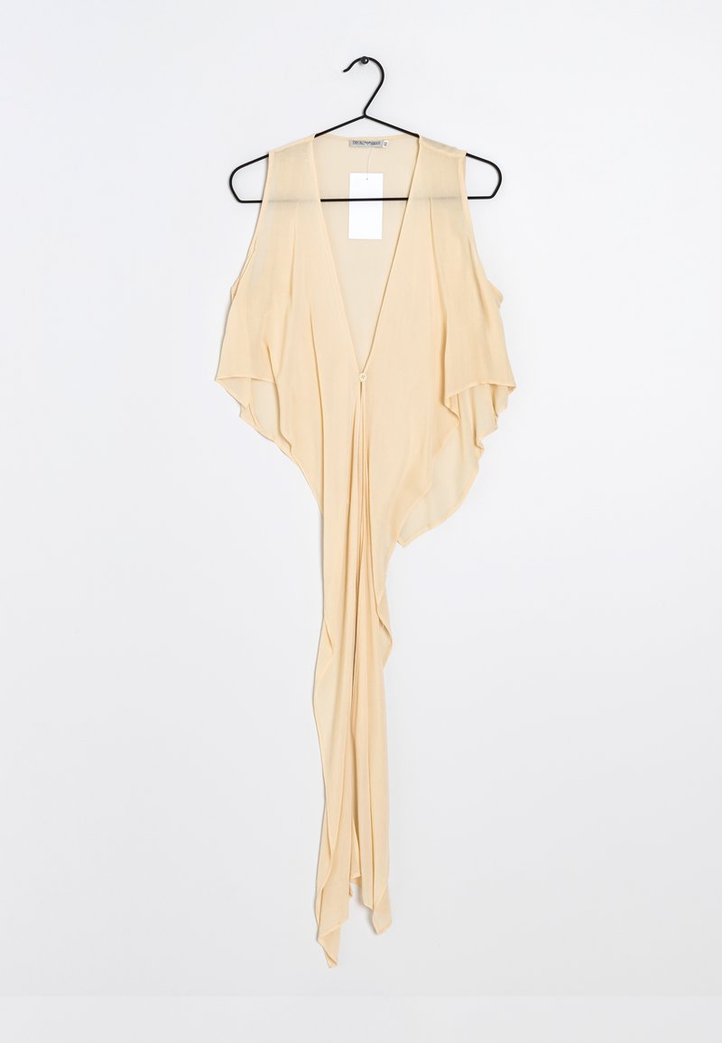 Ljust beige plagg med djup V-ringning, öppna axlar och flödande design. Tillverkat av mjukt tyg, har en knappstängning framtill.
