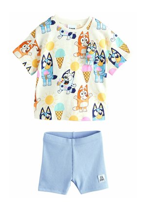 T-shirt a maniche corte con motivi di cani dei cartoni animati e gelato, di colore crema, abbinato a pantaloni corti a coste blu chiaro. La T-shirt ha un colletto rotondo.
