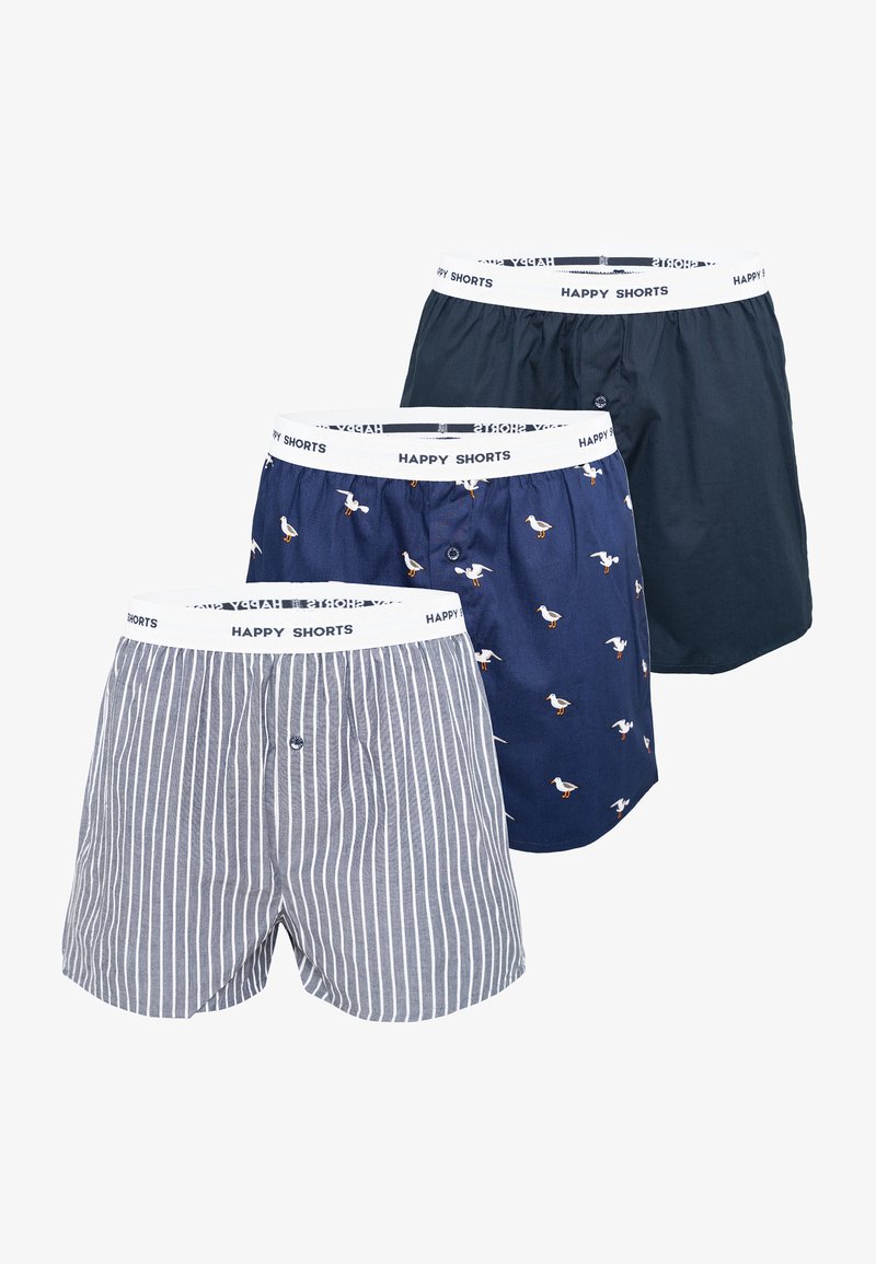 Tři páry boxerů s elastickým bílým pasem označeným "ŠŤASTNÉ KRAŤASY." Jeden pár má modré pruhy, další je tmavě modré barvy a poslední má vzor ptáků.