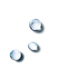 Three clear water droplets of varying sizes on a white surface, exhibiting smooth, rounded shapes and subtle shadows.