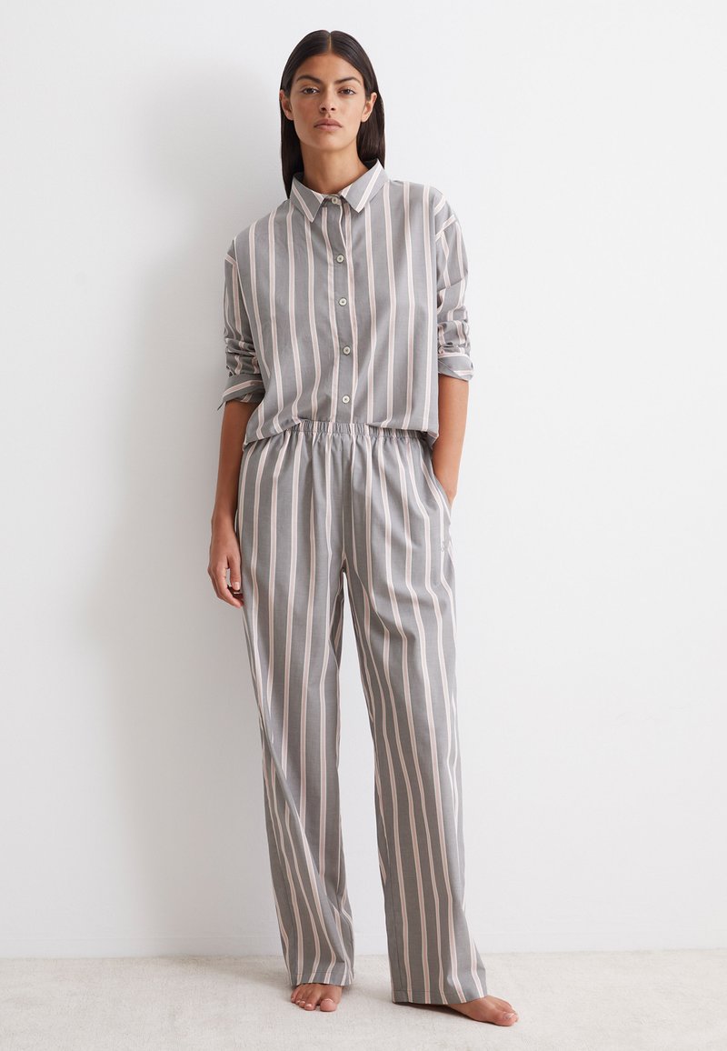 Gestreiftes Pyjama-Set in Grau mit rosa Akzenten. Das Oberteil verfügt über einen Kragen und eine Knopfverschluss; die Hose hat einen elastischen Bund.