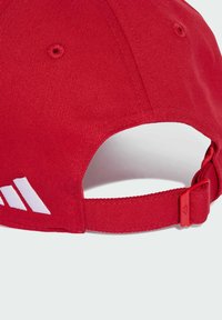 Casquette de baseball en tissu rouge avec une sangle réglable et un logo partiel blanc à l'arrière, présentée sur un fond gris clair.