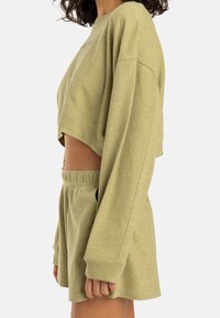 Sweat-shirt court vert clair à manches longues, assorti à un short avec une ceinture élastique et des poches latérales. Texture douce.