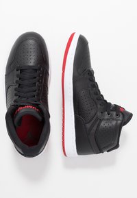 Zapatillas altas de cuero negro con detalles perforados, media suela blanca y acentos rojos en la suela exterior. Cordoneras y forro interior en negro.