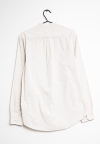 Lange mouwen overhemd met knoopsluiting in lichtbeige stof met een soepele textuur, voorzien van een achterste yoke en een afgeronde zoom.