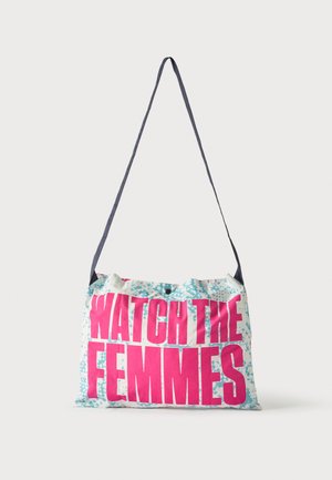 Bolso de tela blanca para el hombro con una larga correa negra y texto en rosa brillante que dice "WATCH THE FEMMES" sobre un fondo azul con estampado.