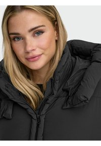 Zwarte pufferjas met een hoge kraag, ritssluiting en grote, gewatteerde schouders; gladde textuur en minimale details.