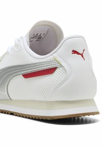 Hvide sneakers med perforeret læder, sølv accenter, røde detaljer og en tekstureret gummisål. PUMA-logo i rødt på hælen.