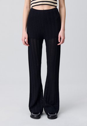 Pantaloni a gamba larga neri in maglia con texture a coste e lavorazione aperta. Vita elasticizzata, lunghi fino al pavimento e con fondo svasato. Design semplice, senza pattern.