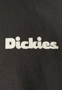 White "Dickies" logo printed on dark gray ribbed fabric background.