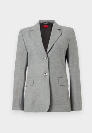 Grå tilpasset blazer med notched lapels, enkle brystknapper, to frontlommer og sølvknapper. Foret innvendig.