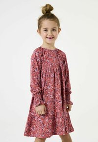 Rotes gemustertes Kleid mit langen Ärmeln und gesmockten Bündchen, das eine fließende Silhouette und Paisleymuster-Details aufweist. Geeignet für Kinder.