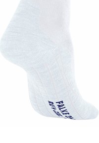 Chaussette blanche à la cheville en tissu texturé avec un texte imprimé bleu marine sur la semelle, présentée sur une forme en pied sur fond blanc.
