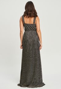 Czarna, sięgająca podłogi sukienka z cienkimi ramiączkami, teksturowana tkanina z pionowymi paskami i dopasowana talia dla uzyskania smukłej sylwetki.