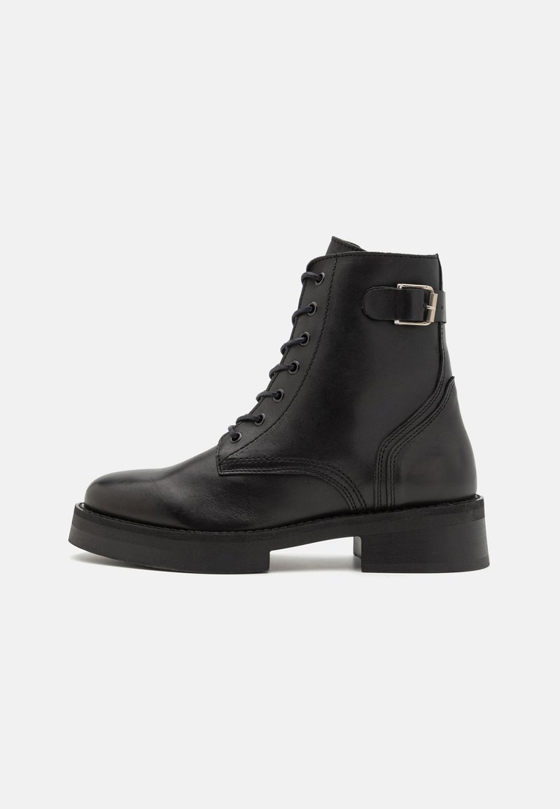 Black leather ankle boot with round toe, lace-up front, and decorative buckle on the side. Features a thick, textured sole.