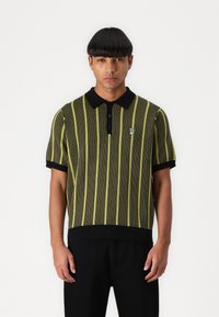 Short-sleeve polo shirt with black and yellow vertical stripes, ribbed collar and cuffs, featuring a small logo on the chest.