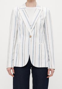 White linen blazer with vertical blue and brown stripes, single button closure, notch lapels, and side pockets. Worn over a white top.