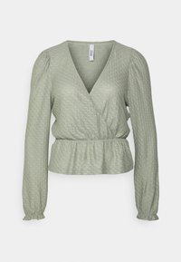Blusa verde de mangas longas com um padrão texturizado, design cruzado e cintura peplum. Apresenta um decote em V profundo e mangas folgadas.