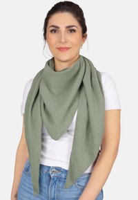 Écharpe verte et texturée en forme triangulaire, drapée autour du cou. Fabriquée en matériau doux avec un motif de fronces visible.