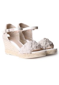 Sandalias de cuña con parte superior de tejido trenzado en beige claro, cuentan con una tira de dedo trenzada y una correa al tobillo, sobre una plataforma de cuerda de yute.