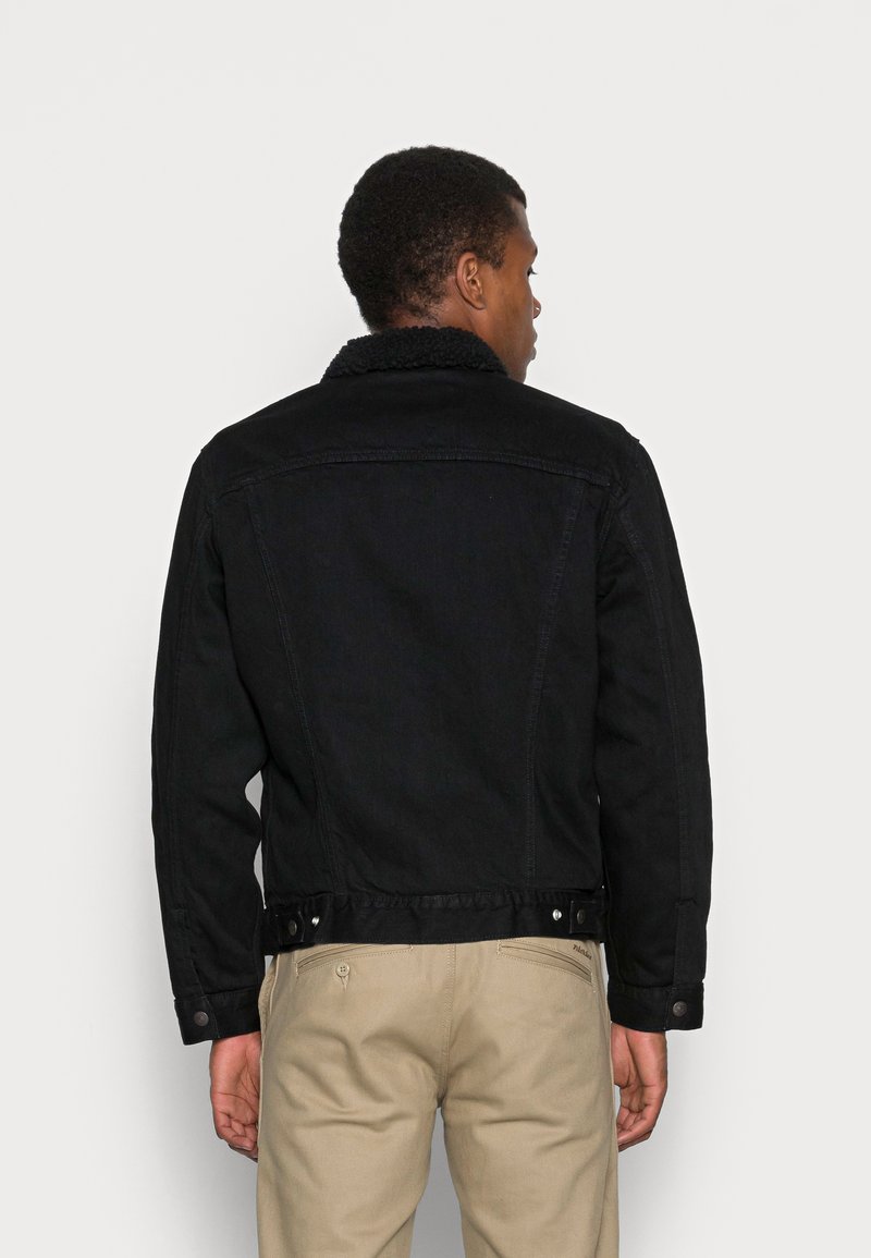 Czarna dżinsowa kurtka z teksturowanym kołnierzem, zapięciem na guziki i dopasowanym krojem. Posiada widoczne szwy i lekko skróconą długość.