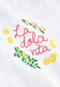 Tissu blanc avec texte cursif rouge "La dolce vita" entouré de citrons jaunes, de feuilles vertes et de petites fleurs roses.