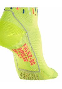 Gelbe Sportstrumpf mit bunten Punktmustern, verstärkter Ferse und dem in fettem Pink aufgedruckten Text "FALKE-BC IMPULSE". Leichtes, atmungsaktives Material.