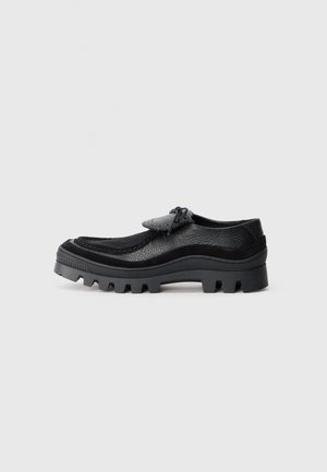 Black casual shoes featuring a textured leather upper, rounded toe, and a sturdy lug sole for traction. Decorative lacing detail at the front.